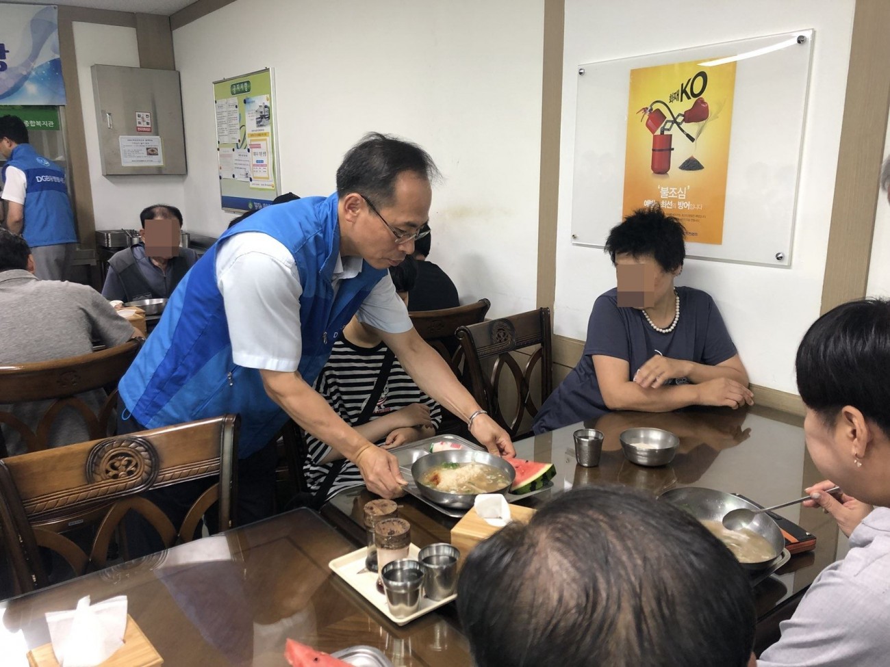 식판에 음식을 담아 이동이 불편한 이용고객에게 가져다 주는 봉사자 모습