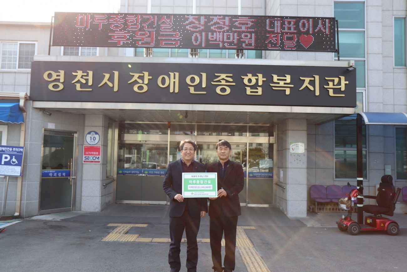 복지관을 배경으로 사진을 찍고 있는 박홍열관장, (주)마루종합건설 장정호 대표이사